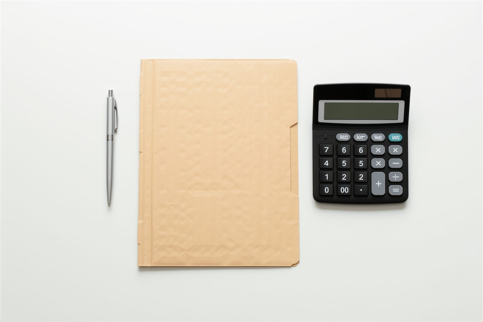 A closed manila folder, a black pen and a desk calculator laid out on a pale wooden desktop in raking sunlight